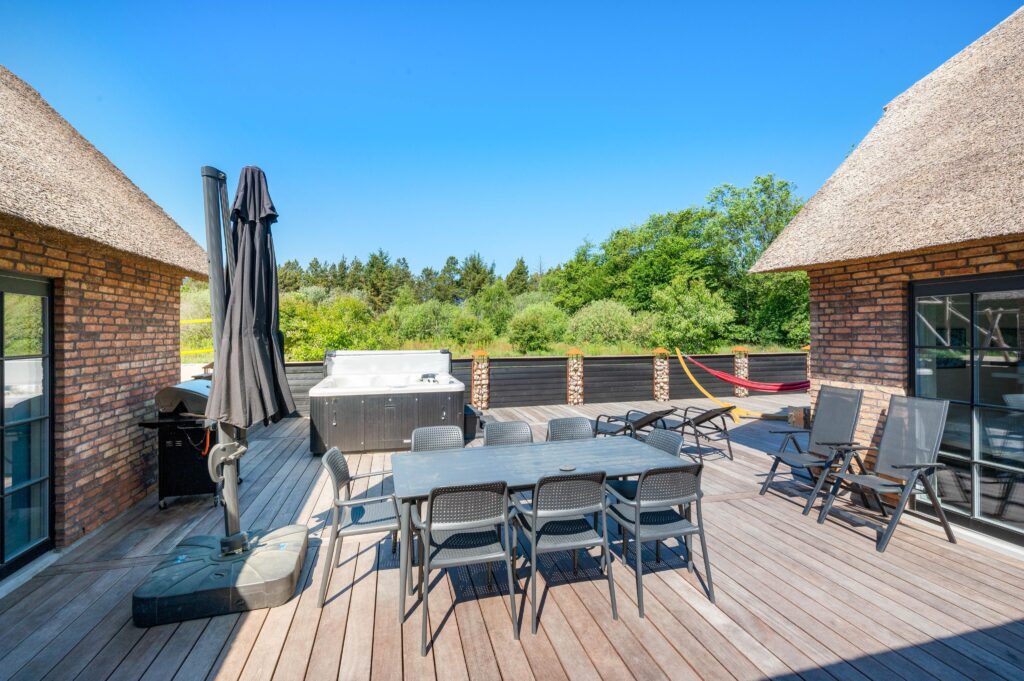 Terrasse med spisebord, stole og solsenge