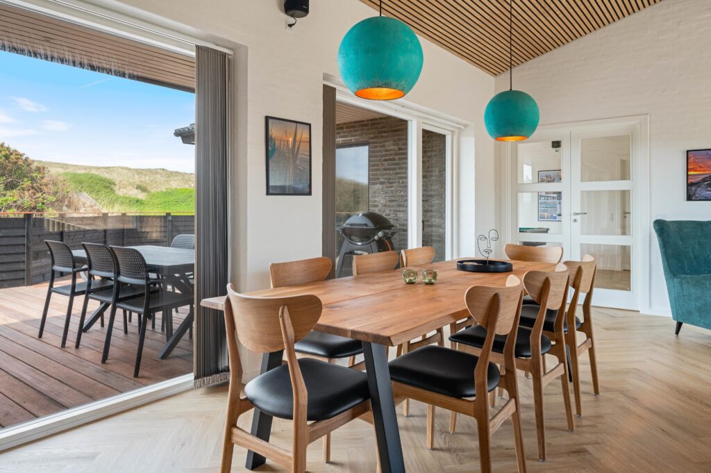 Spisestue med massivt træbord, stole og turkise pendullamper — gardiner synlige