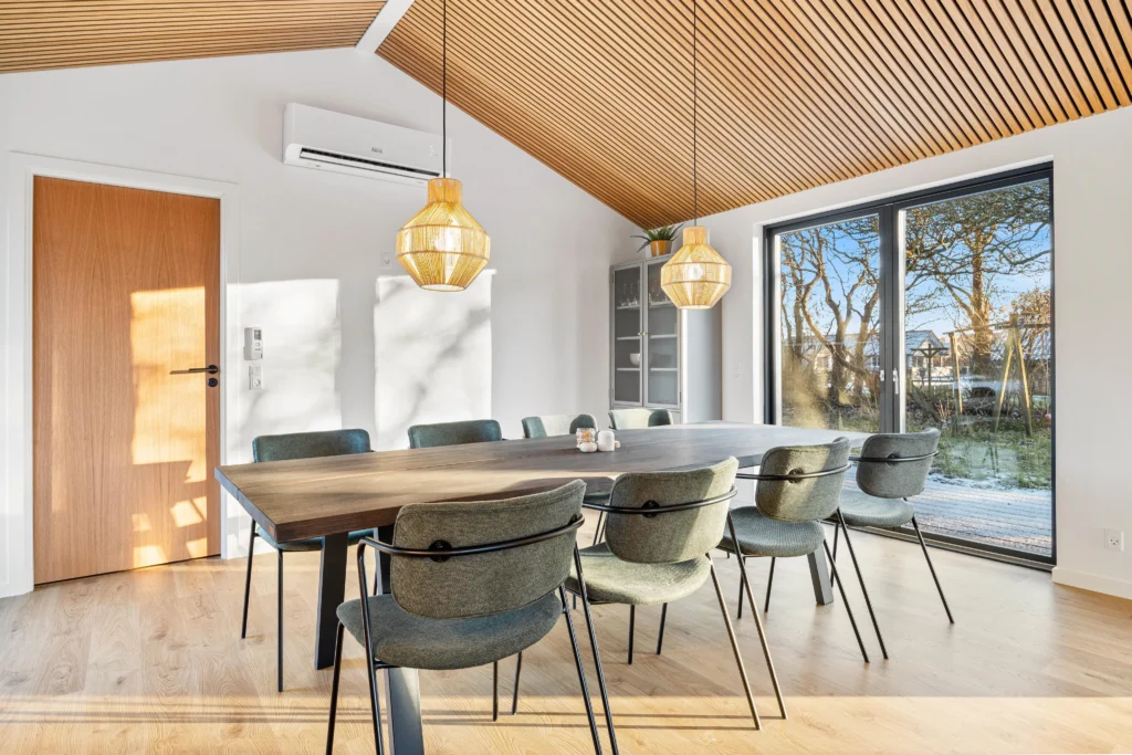 Spisebord med stole og rattan-hængelamper i sommerhus