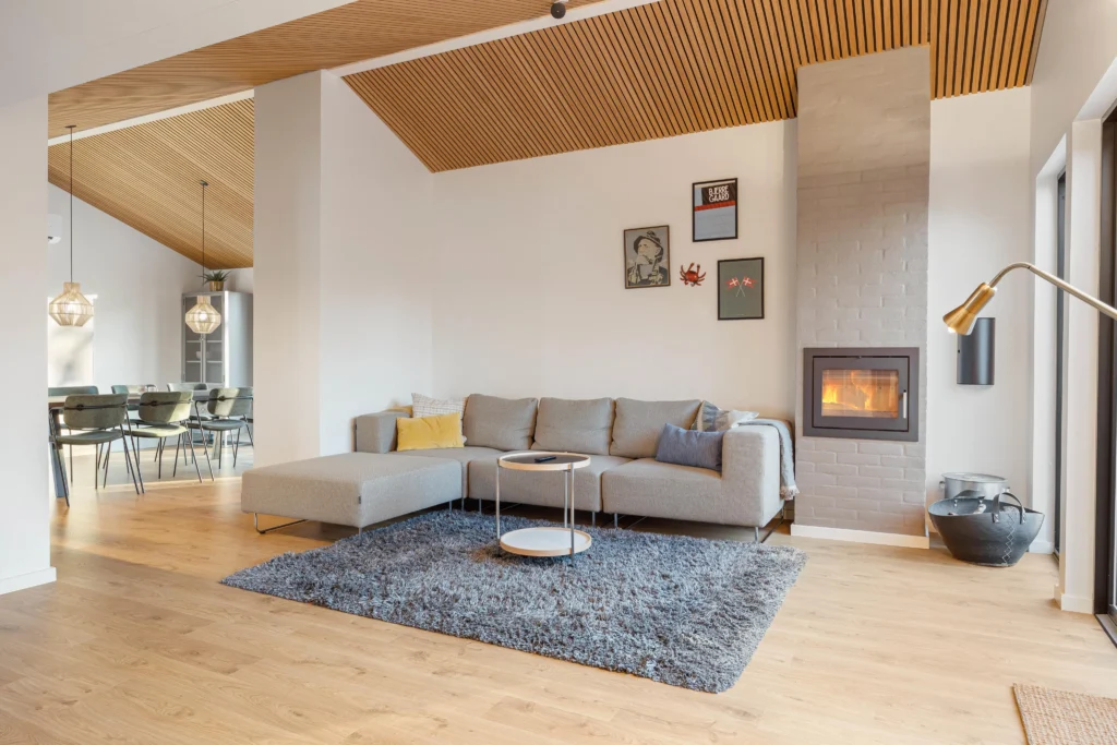 Stue med sofa, pejs og gulvlampe i lyst sommerhus