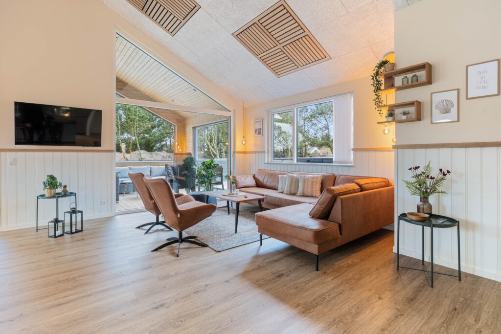 Langt træspisebord med stole og hængelamper over bordet i lys og rummelig spisestue