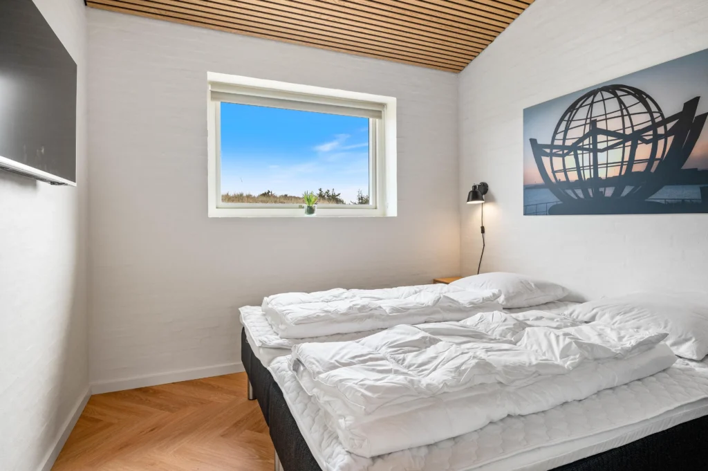 Lyst soveværelse med dobbeltseng og væglampe