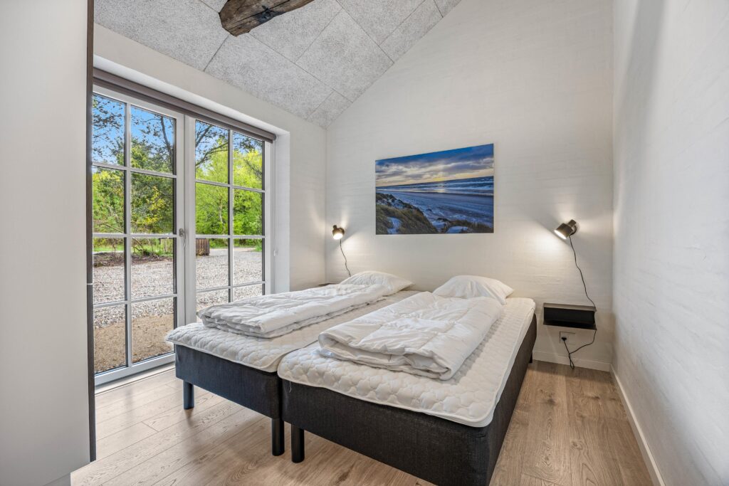 Soverum med to enkeltsenge, væglamper og kunsttryk med havmotiv