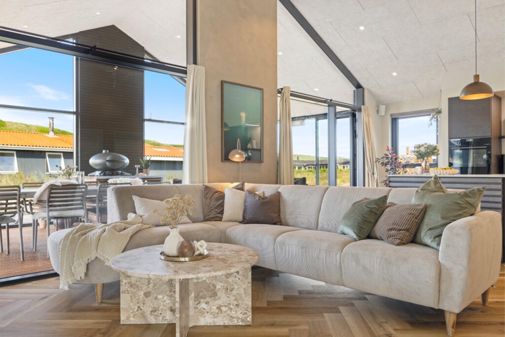 Stue med stor hjørnesofa og sofaborde mod panoramavinduer