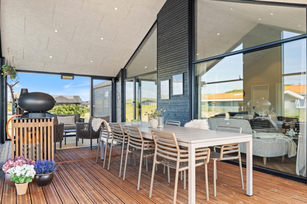 Overdækket terrasse med udendørs spisebord og stole